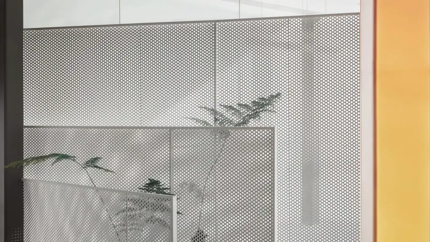 Perforated metal interior room divider balancing privacy light and visibility