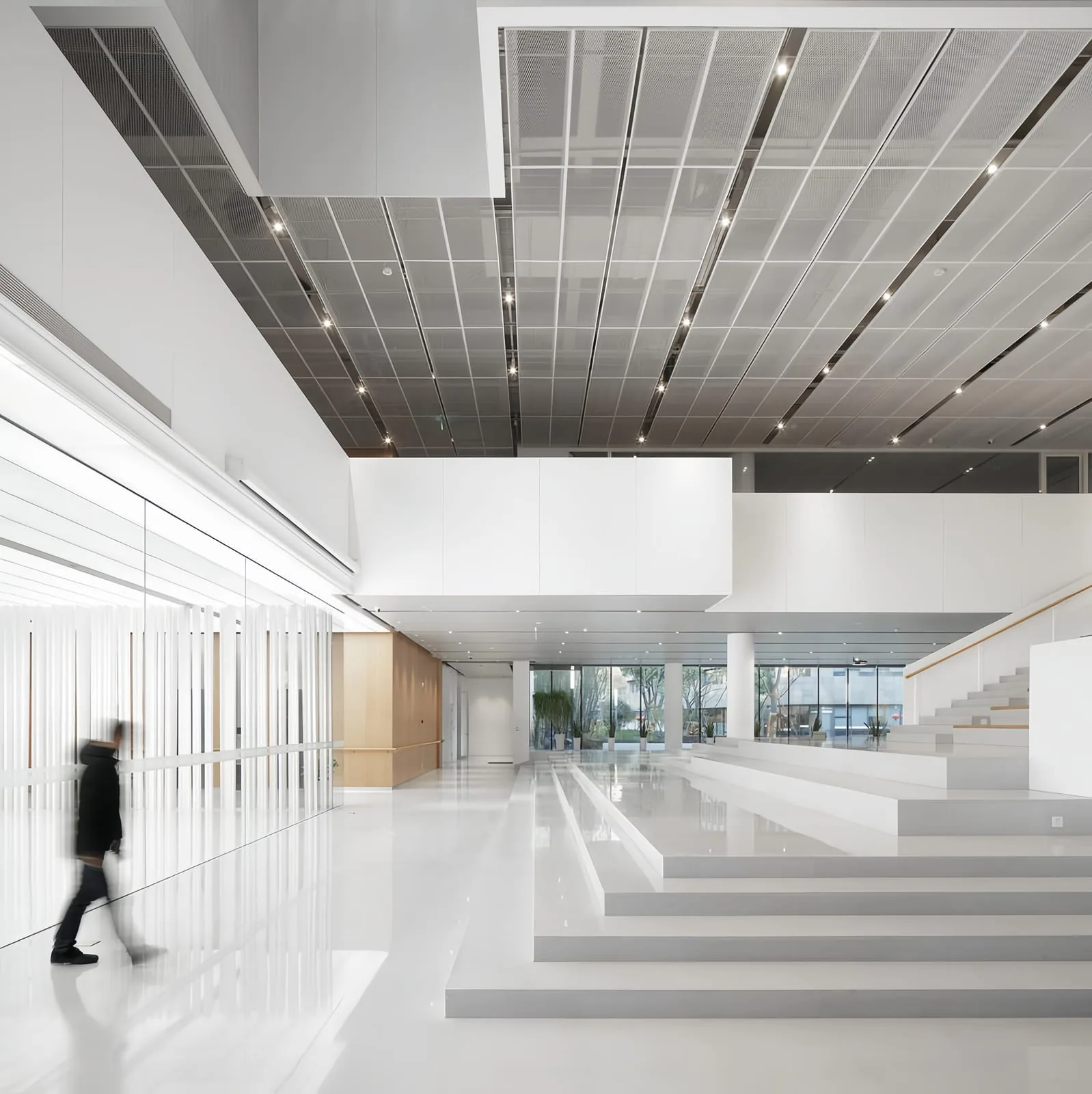 Architectural metal mesh ceiling panels coordinated with linear lighting
